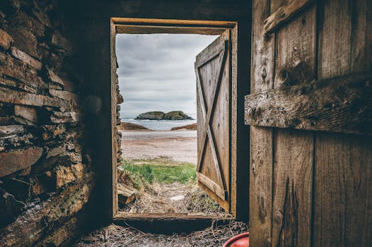 A rustic wooden doorway frames a picturesque beach view with an island in the distance.