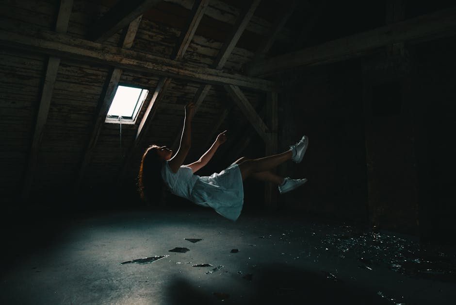 A surreal photograph of a woman in a white dress floating in an abandoned attic, capturing a sense of mystery.